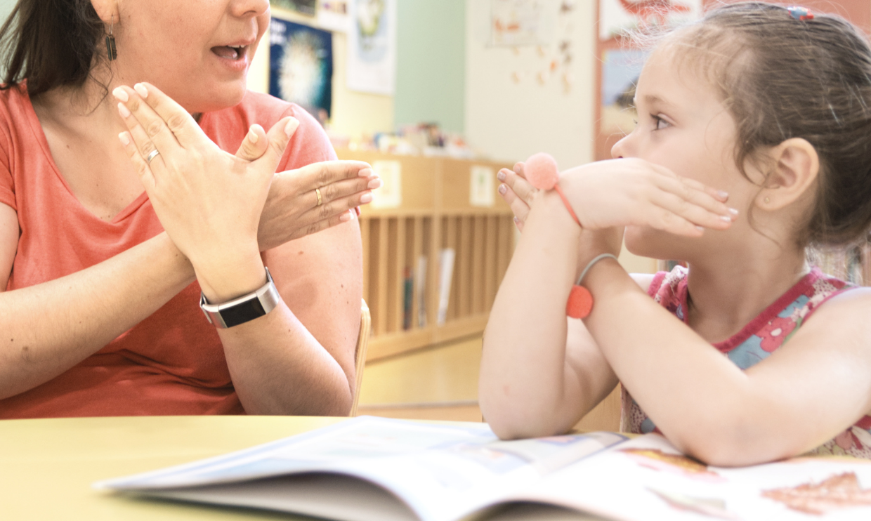 Adult teaching child a sign