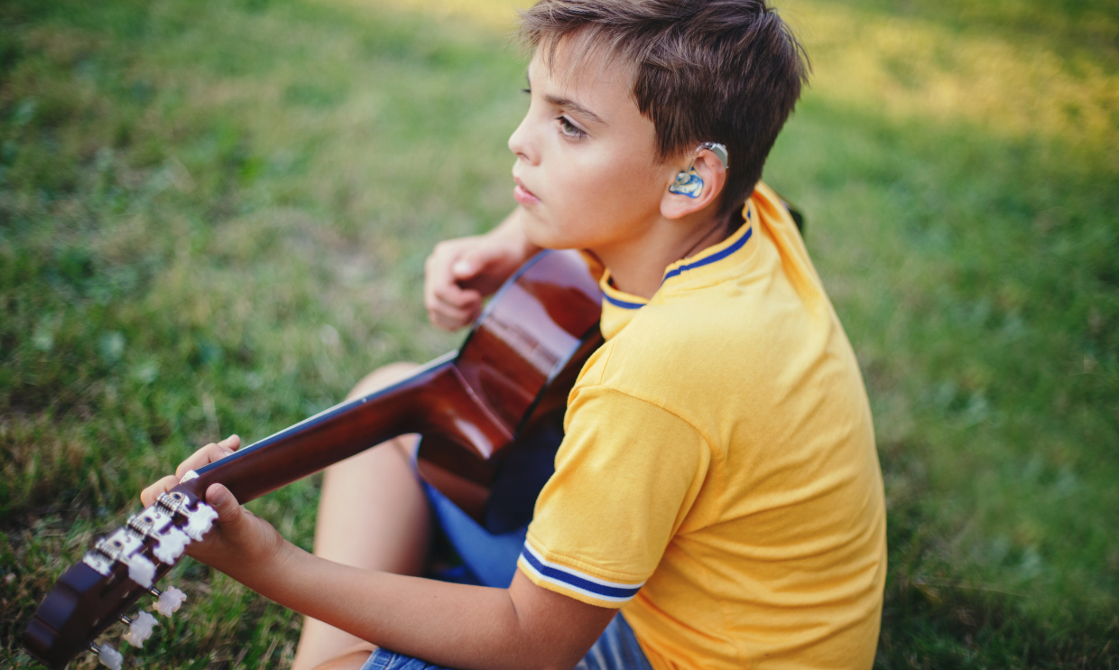 Boy with hearing aid playing the guitar