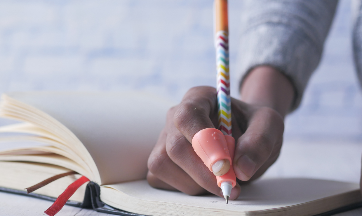 Child writing using a pencil grip